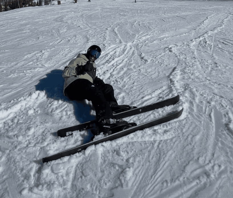 Lapo sitting in snow on skis giving a thumbs up after a fall