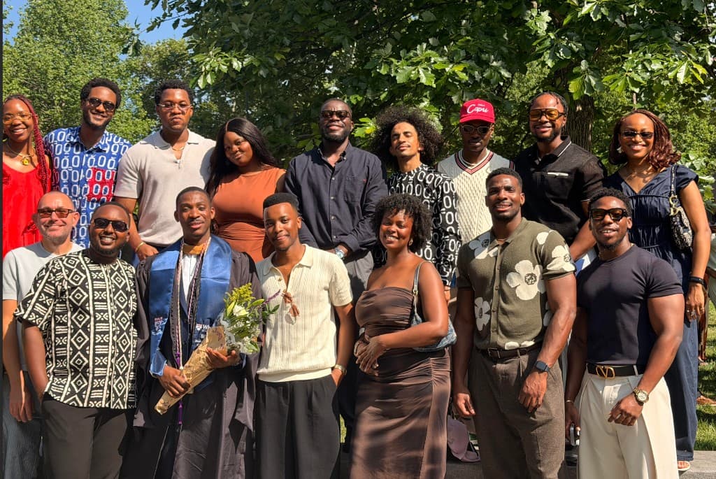 Lapo in graduation gown with friends and flowers outdoors