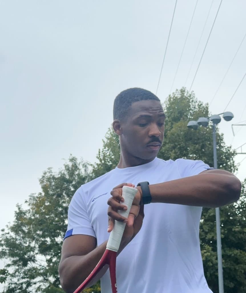 Lapo on a tennis court checking his watch between points, racket in hand